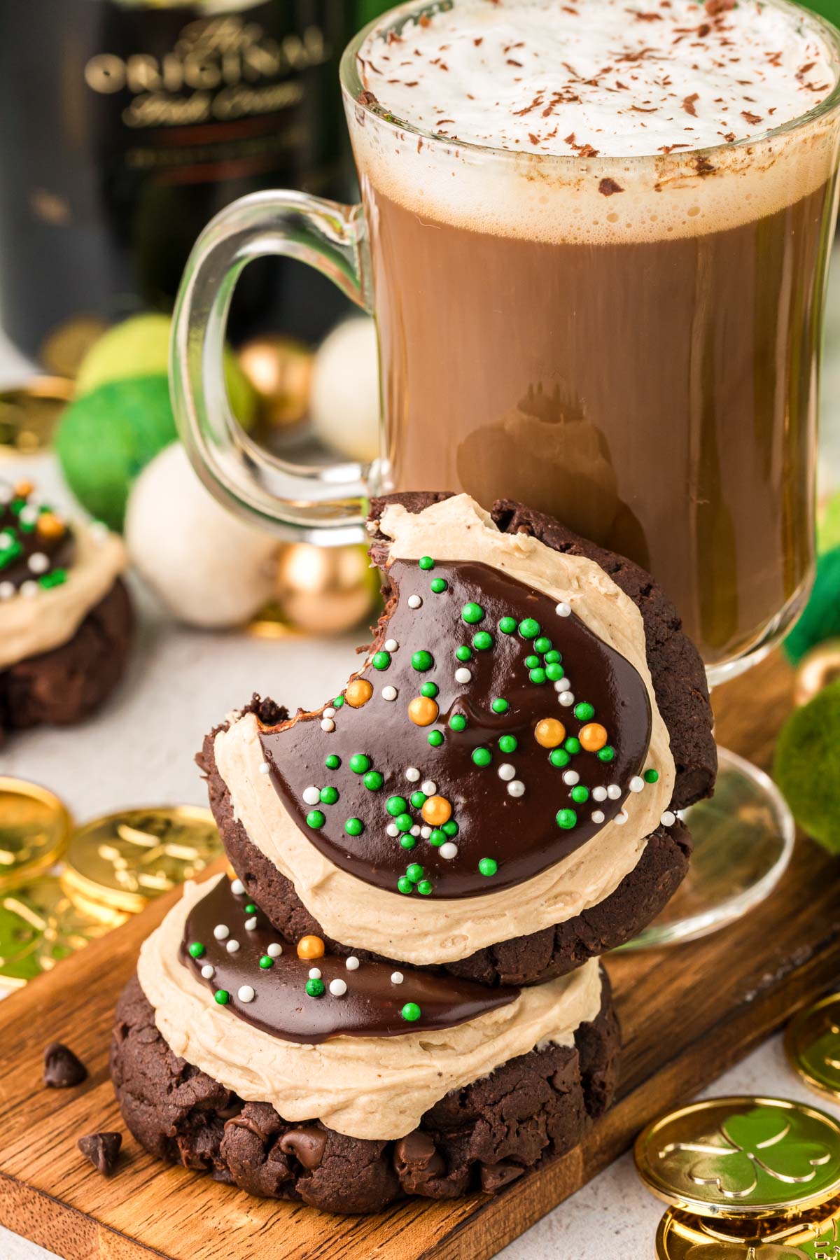 Two Irish Cream Cookies next to an Irish Coffee, one is on top of the other with a bite missing.