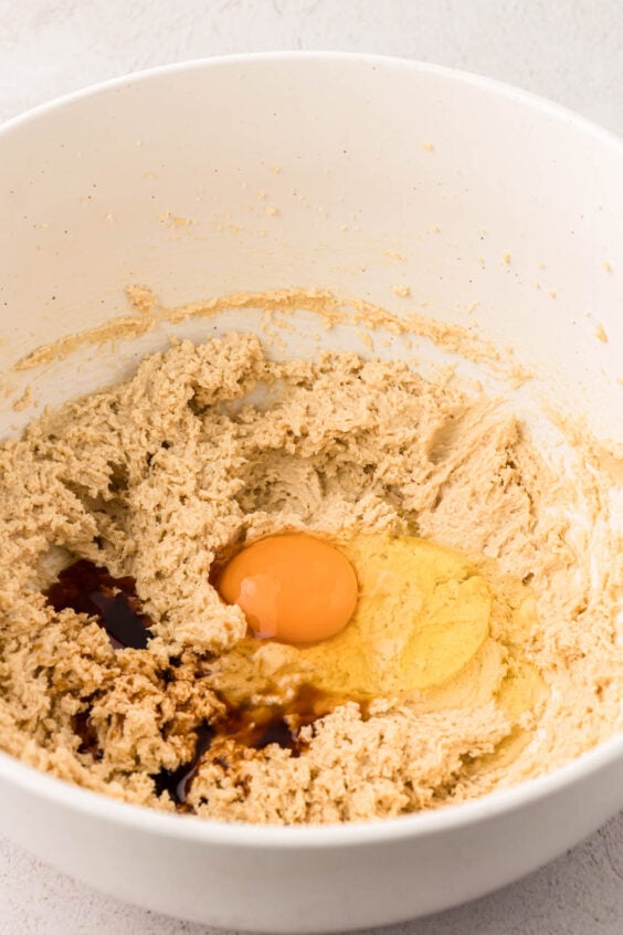 Egg and vanilla added to creamed butter and sugar in a mixing bowl.
