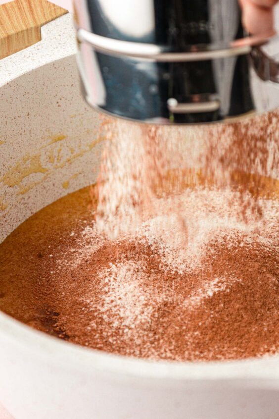 Dry ingredients being sifted into wet ingredients to make brownie batter.