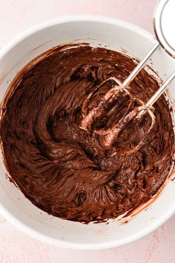 Butter and cocoa creamed together in a bowl with a stand mixer.