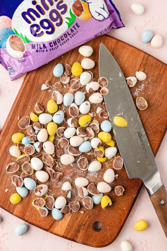 Chopped Mini Cadbury Eggs on a cutting board with a knife.