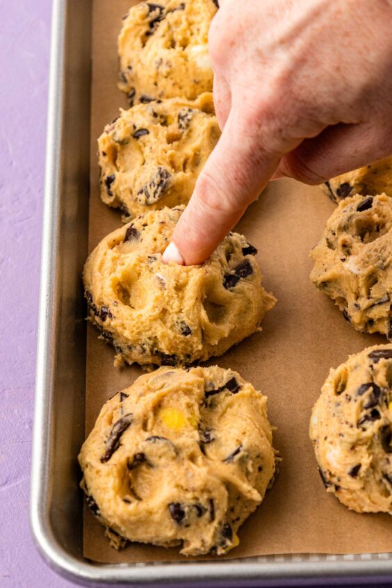 Balls of cookie dough on a parchment lined baking sheet.