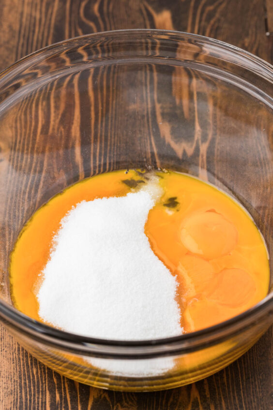 Egg yolks and sugar in a glass bowl.
