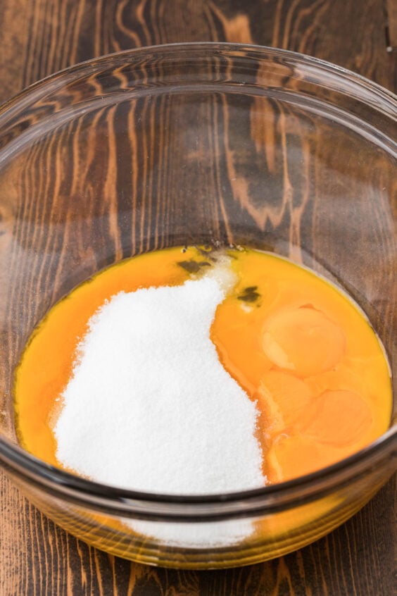 Egg yolks and sugar in a glass bowl.