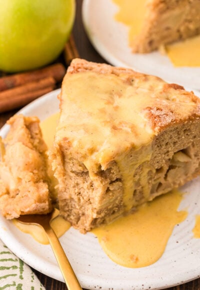 A slice of Irish Apple Cake on a white plate with a fork with a bite on it.