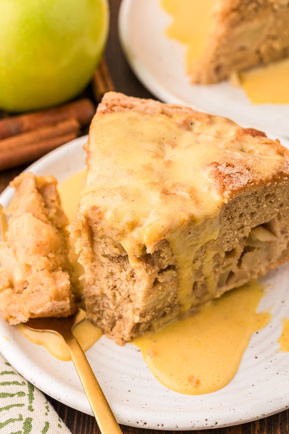 A slice of Irish Apple Cake on a white plate with a fork with a bite on it.