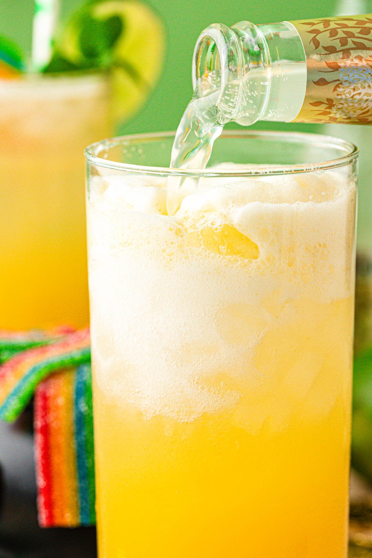 Ginger beer being poured into a yellow mocktail.
