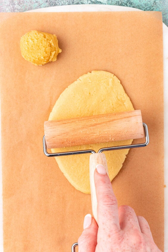 A pastry roller rolling out balls of cookie dough.