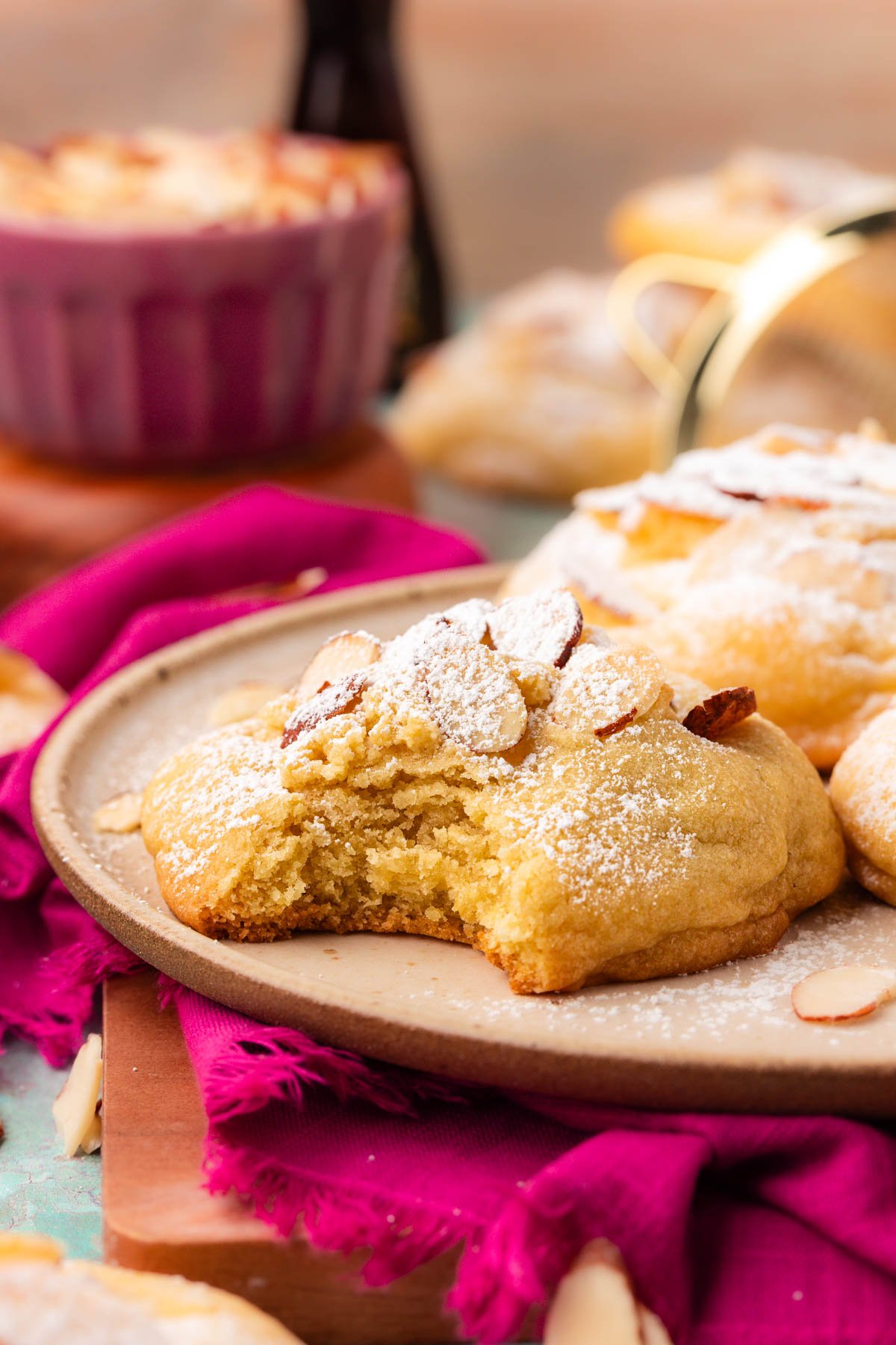 Almond Croissant cookies on a plate with one missing a bite.