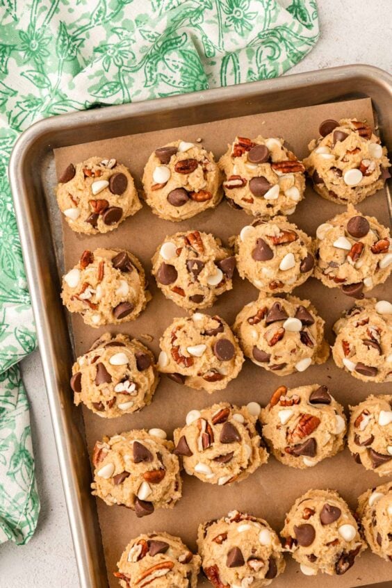 Scoops of cookie dough on a parchment lined baking sheet.