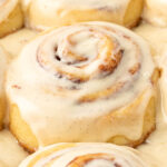 Close up of iced cinnamon rolls on a pan.
