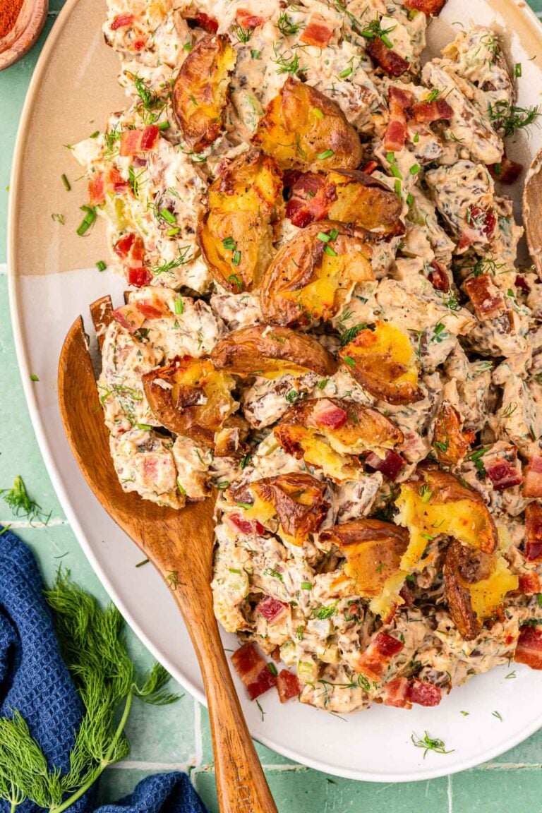 A wooden spoon resting in a bowl of potato salad.