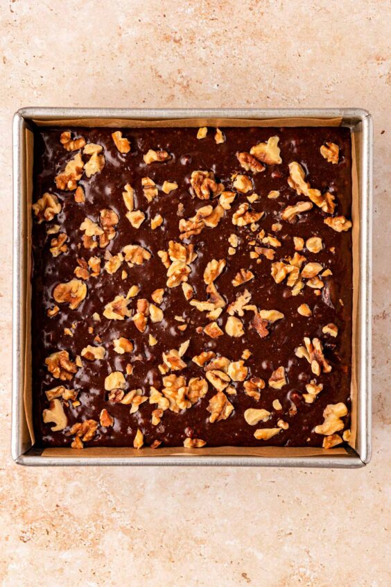 Brownie batter in a pan topped with walnuts.