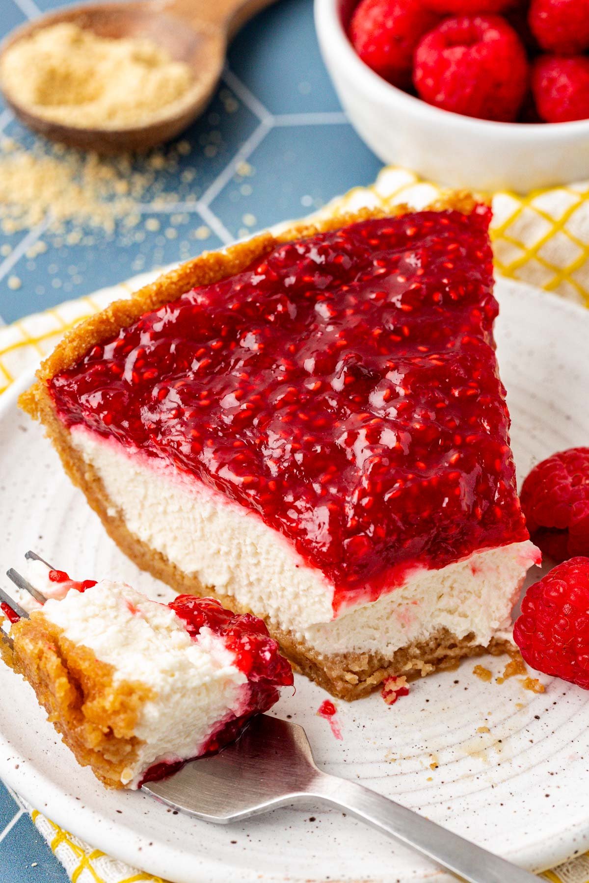 A slice of raspberry cream pie with a bite missing on a plate.
