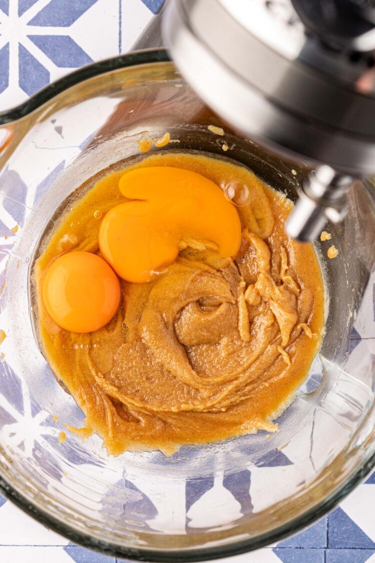 Eggs being added to wet ingredients in a mixing bowl.