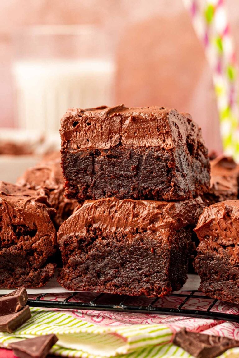 Close up of frosted brownies on a plate. Two stacked on top of each other in the front.