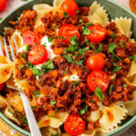 A teal bowl filled with Turkish pasta with a fork sitting on the side of the bowl.