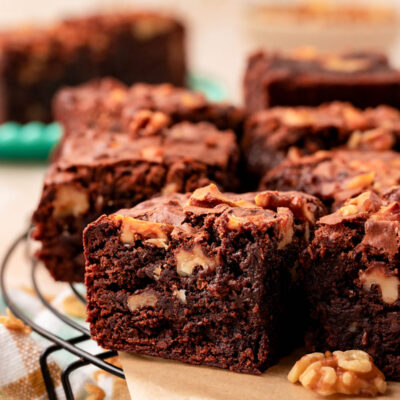 Close up of a brownie with walnuts on a piece of parchment paper.