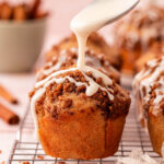 Icing being drizzled over the top of cinnamon muffins.
