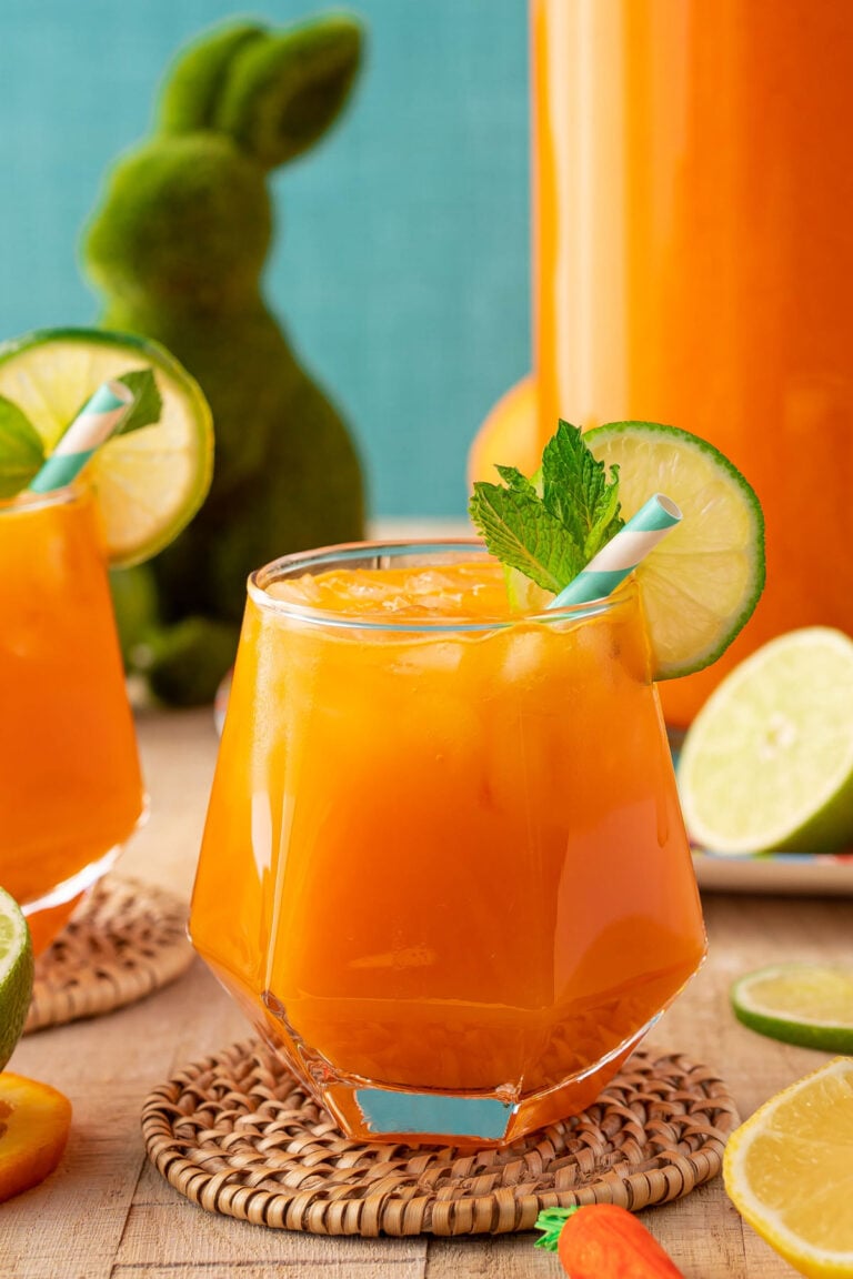 Close up of a glass of orange punch with Easter decor in the background.