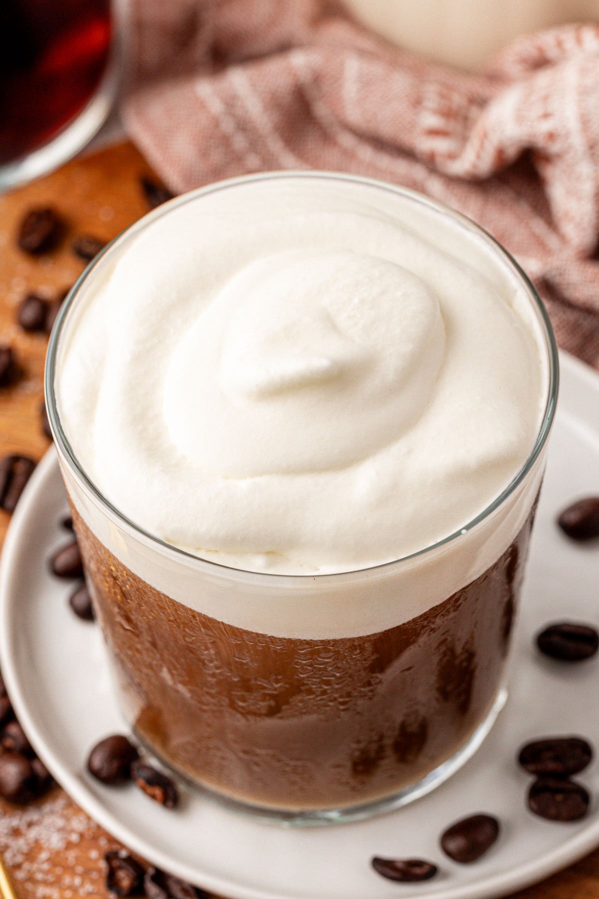 Close up of a glass filled with cold brew coffee and topped with homemade vanilla cold foam.