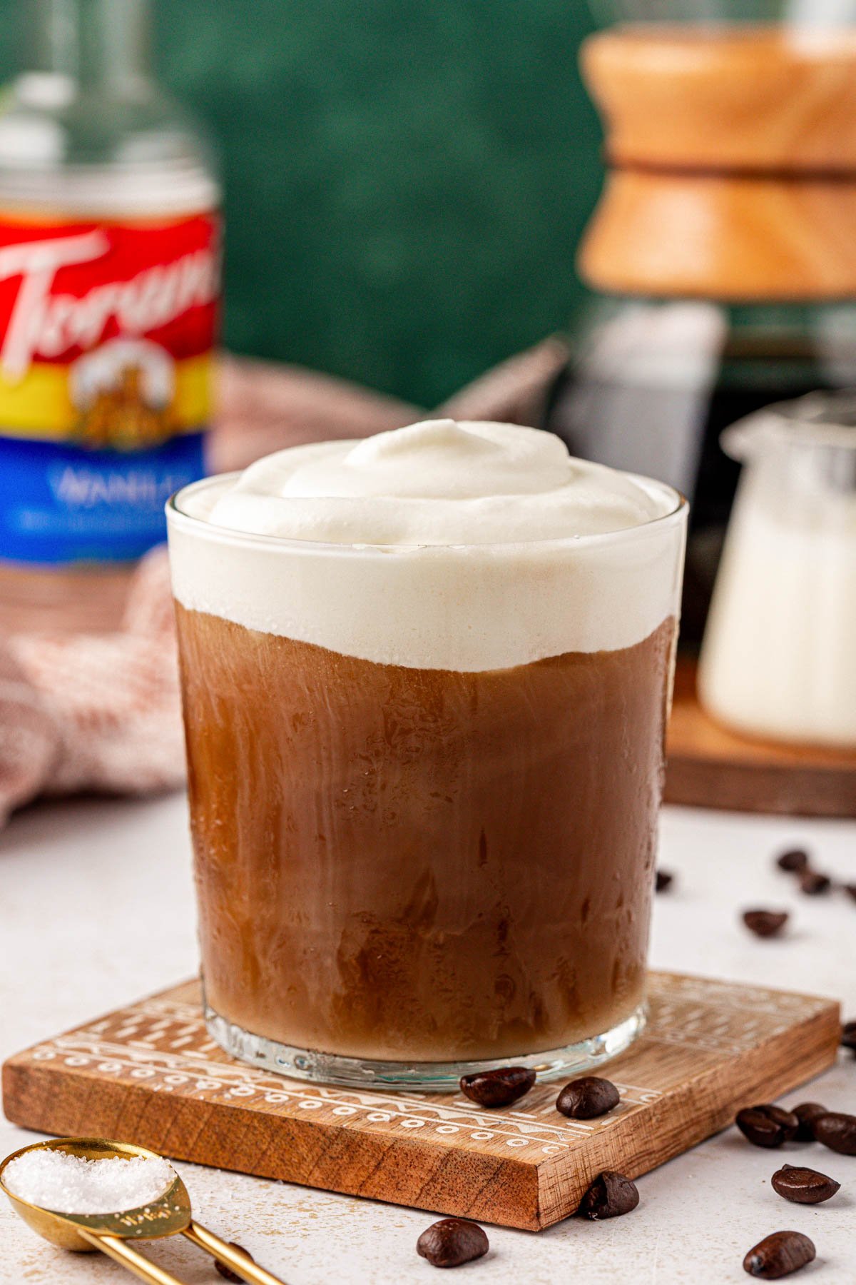 Close up of a glass of iced coffee topped with cold foam.