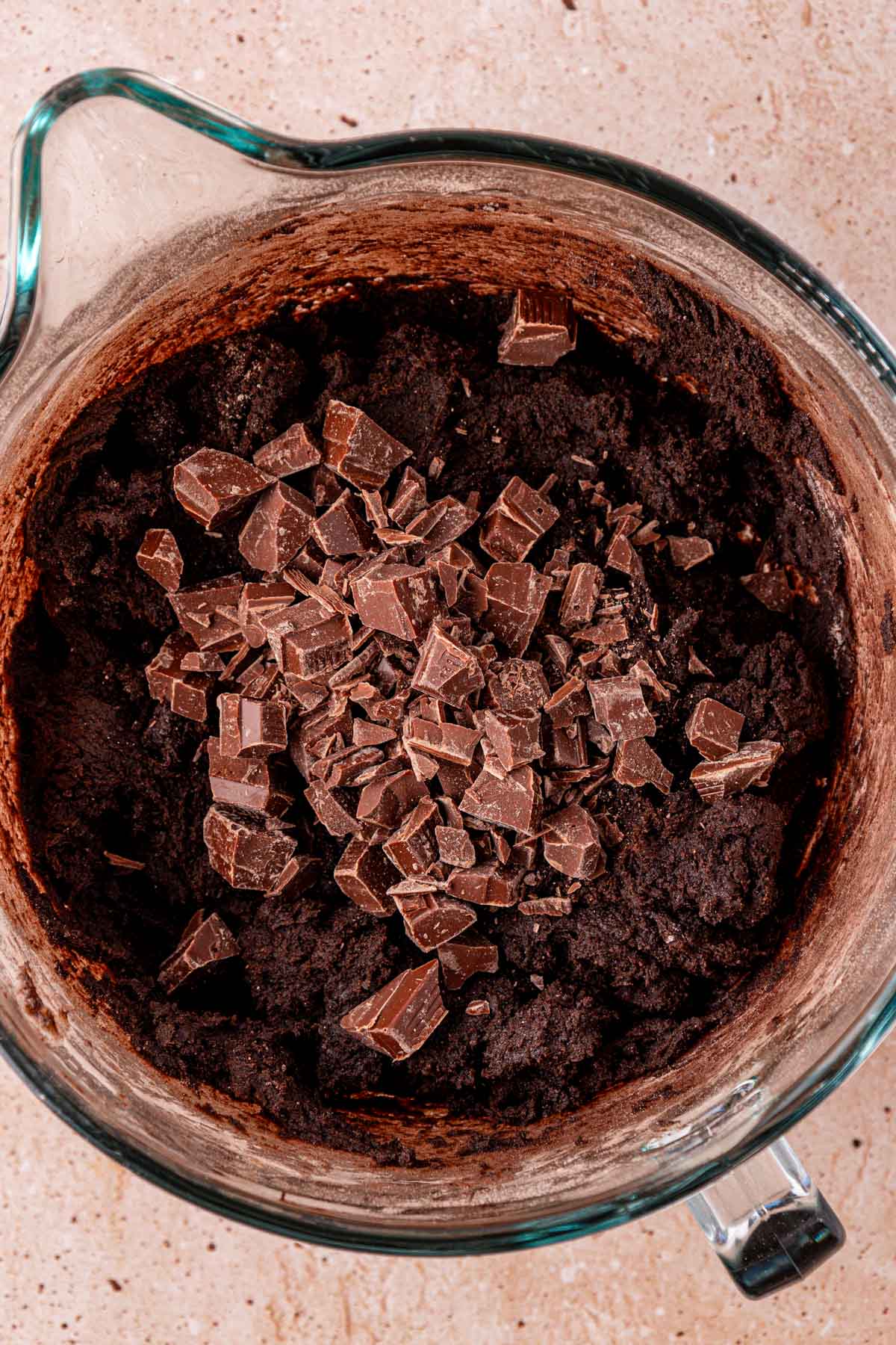 Chocolate chunks being added to a bowl of chocolate cookie dough.