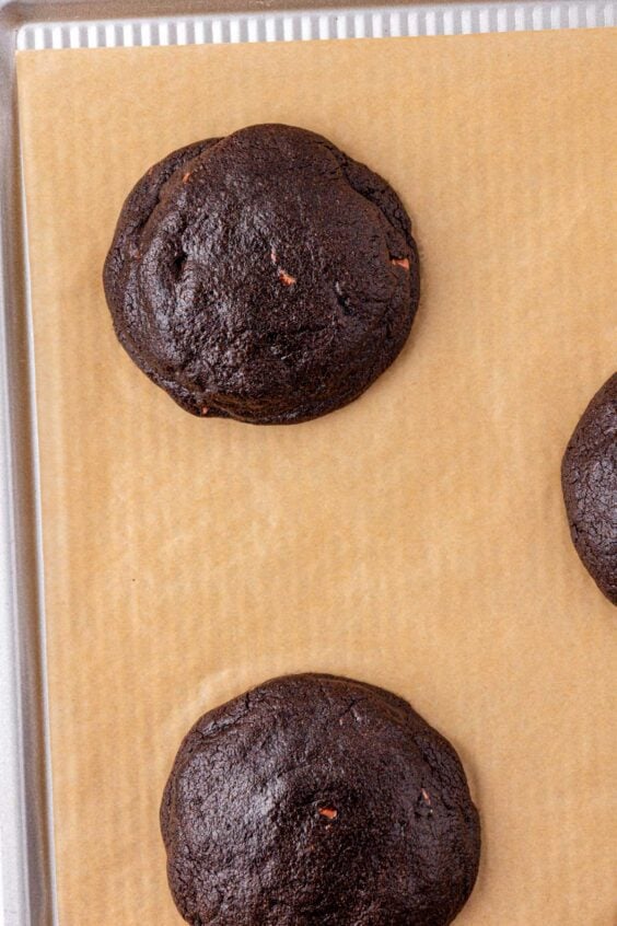 Close up of chocolate cookies on a parchment lined baking sheet.