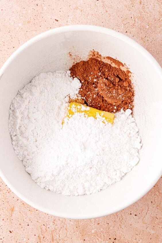 Sugar, cocoa powder, and butter in a white mixing bowl.