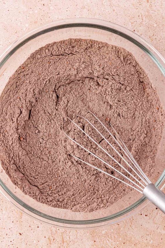 Dry ingredients for chocolate cookies being whisked in a mixing bowl.