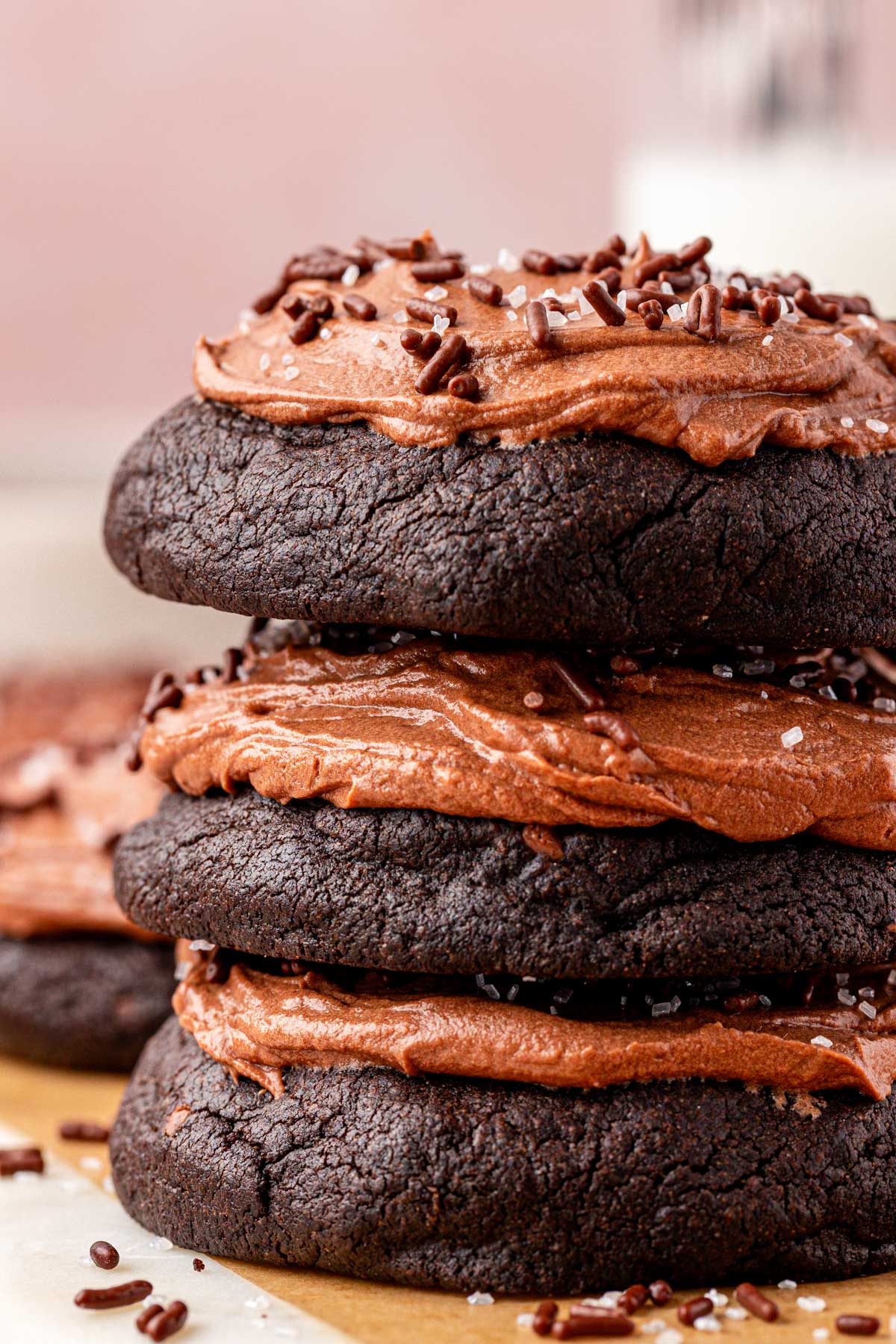 Close up of 3 frosted chocolate cookies stacked on top of each other on a table.