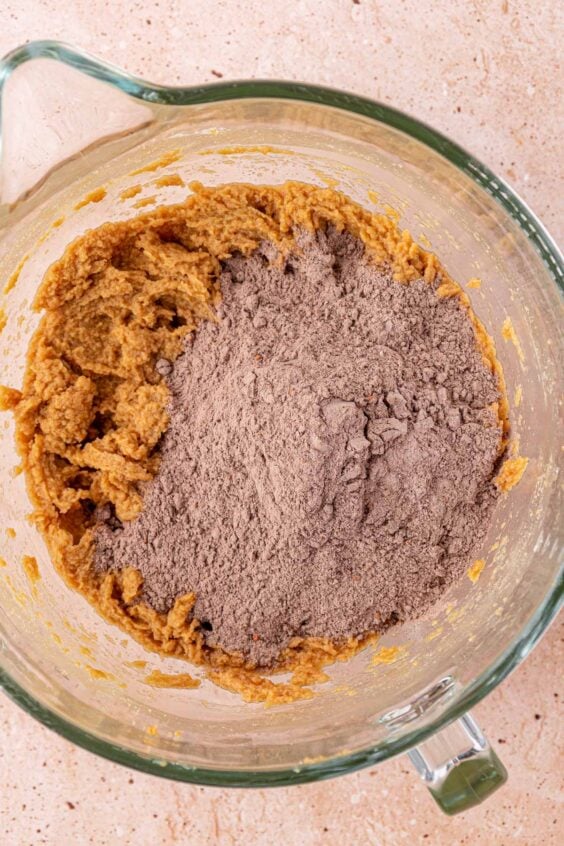 Dry ingredients being added to wet ingredients in a mixing bowl.