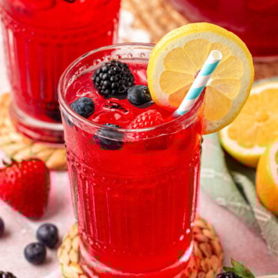 Close up of a glass filled with berry lemonade on a rattan coaster.