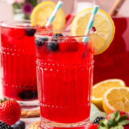 Two glasses of berry lemonade on a table.