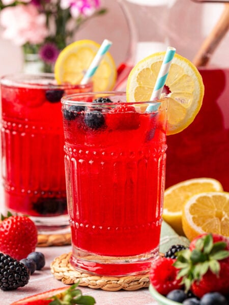 Two glasses of berry lemonade on a table.
