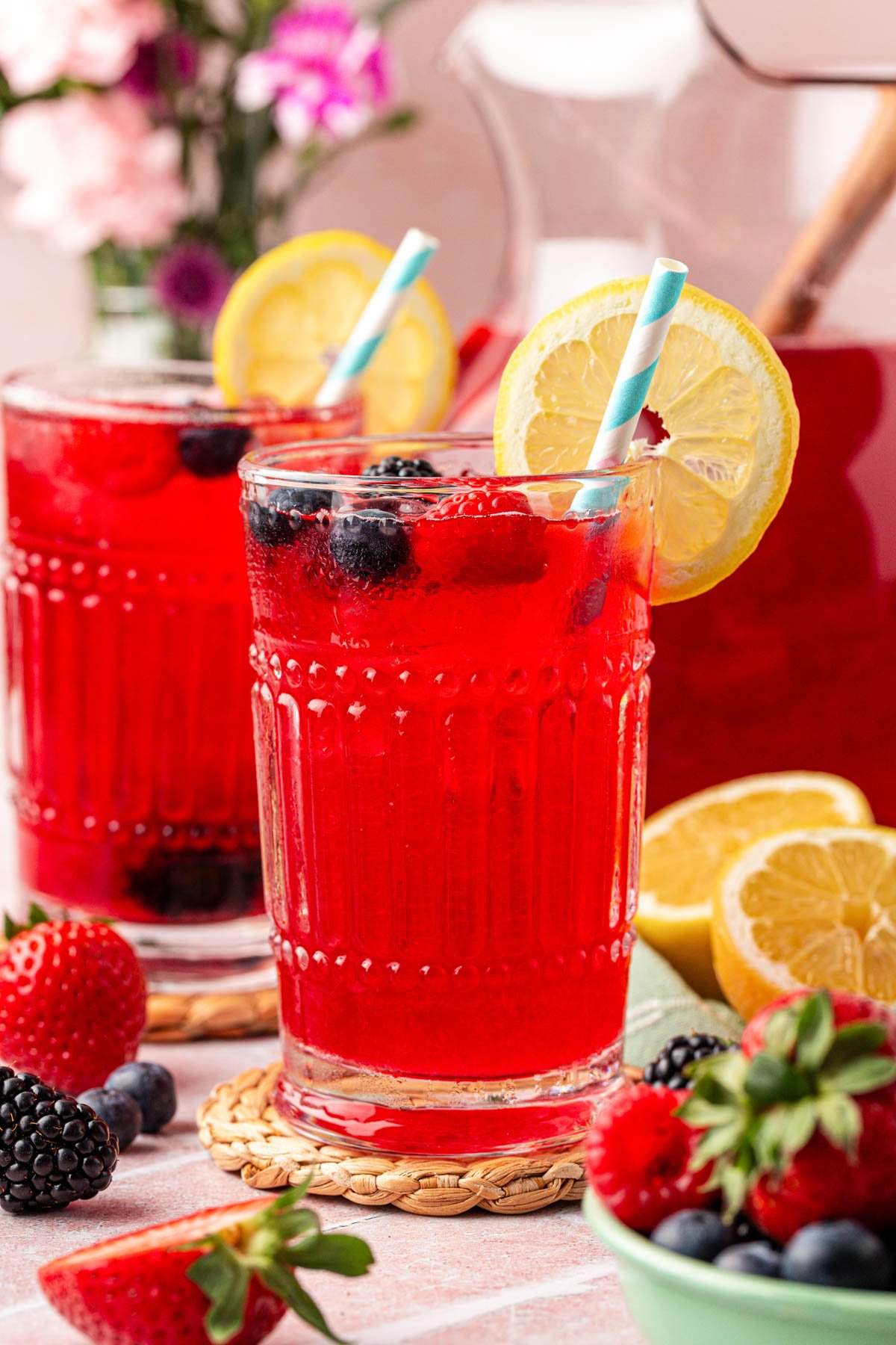 Two glasses of berry lemonade on a table.