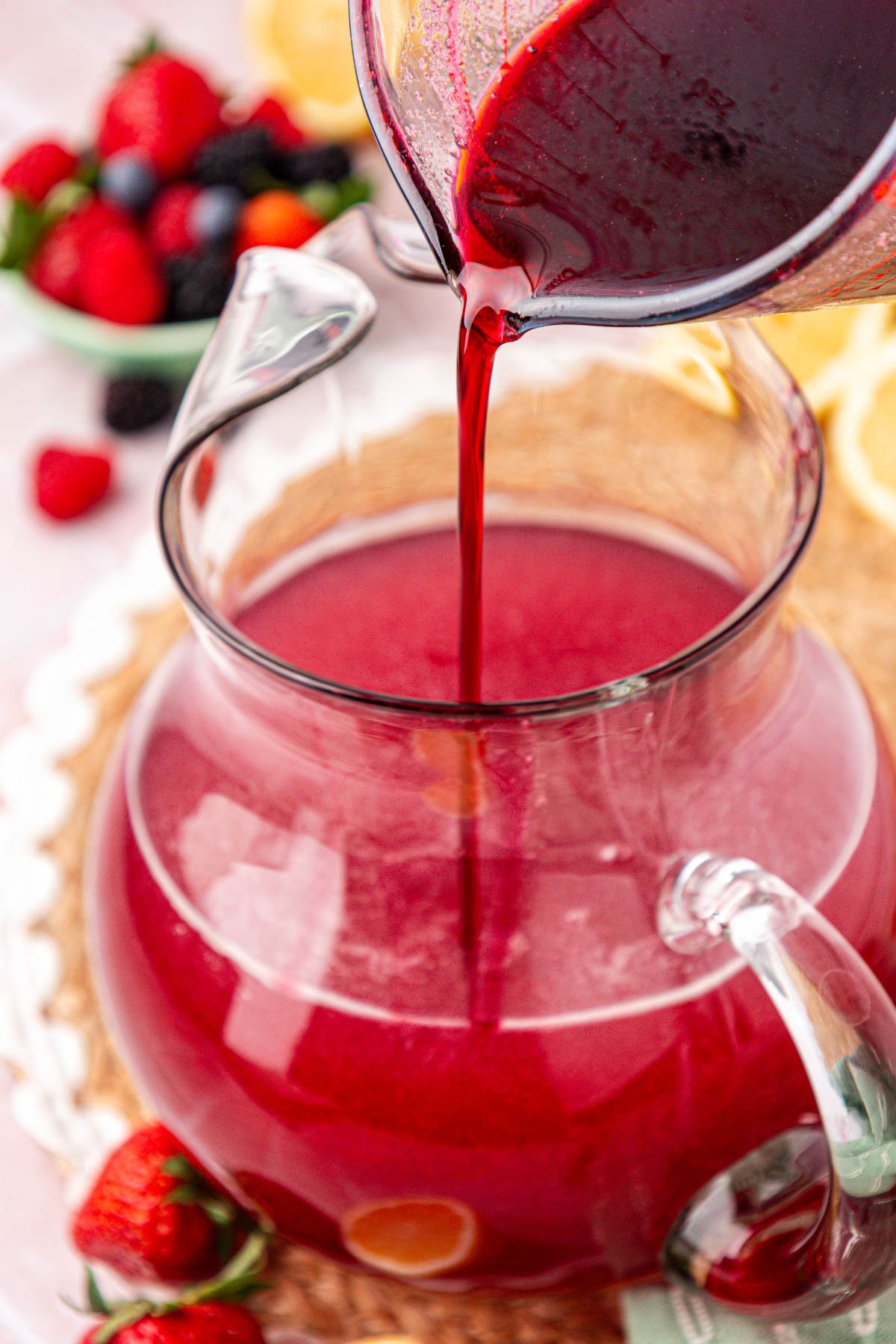 Berry simple syrup being poured into a pitcher of lemonade.