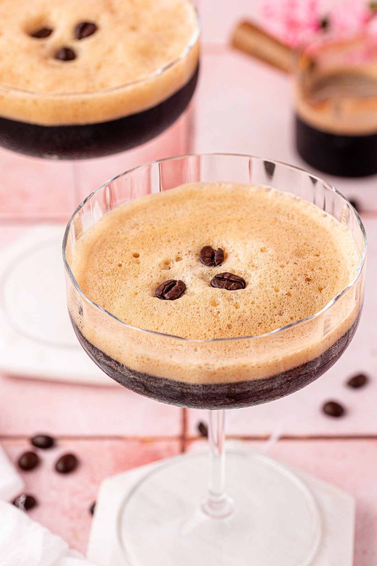 Close up of a coupe glass with a cafe shakerato drink in it with another in the background.
