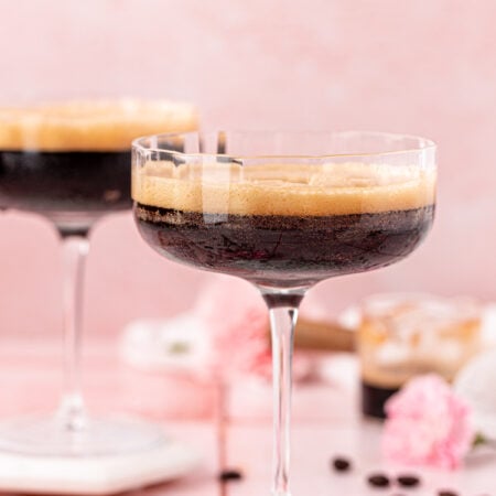 Two coupe glasses with non alcoholic espresso martinis in them.