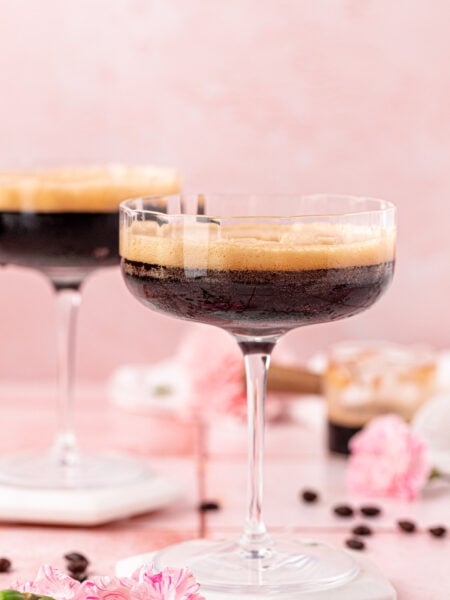 Two coupe glasses with non alcoholic espresso martinis in them.