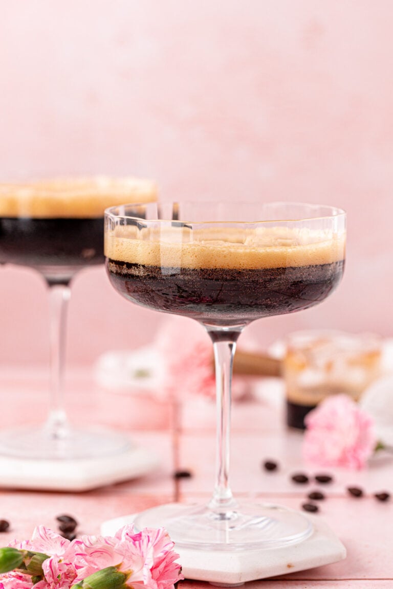 Two coupe glasses with non alcoholic espresso martinis in them.