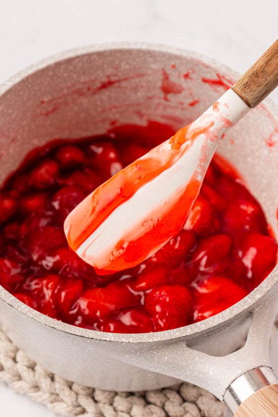 Strawberry filling in a pot with a mixing spatula showing consistency.