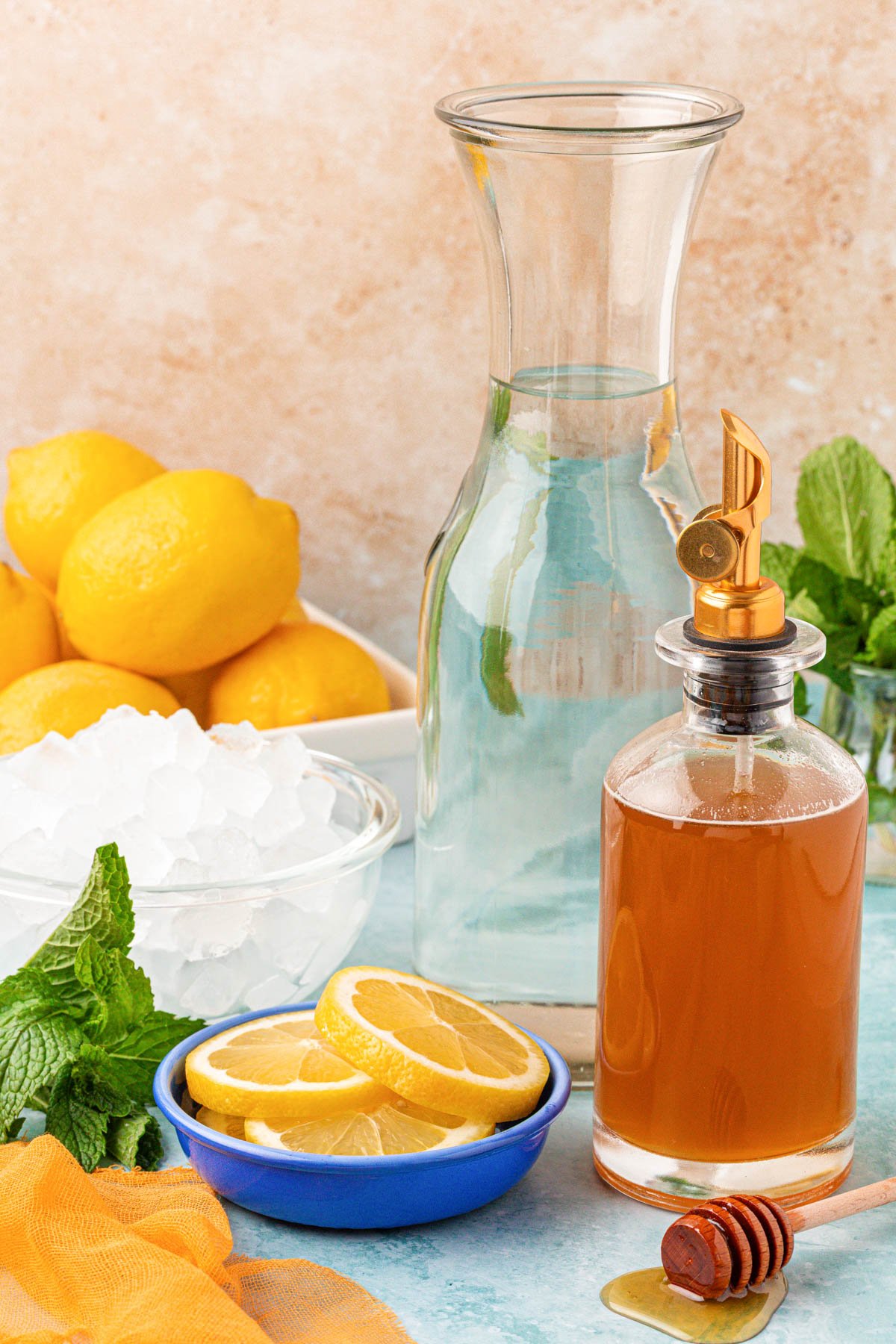 Ingredients to make lemonade with honey on a blue table.
