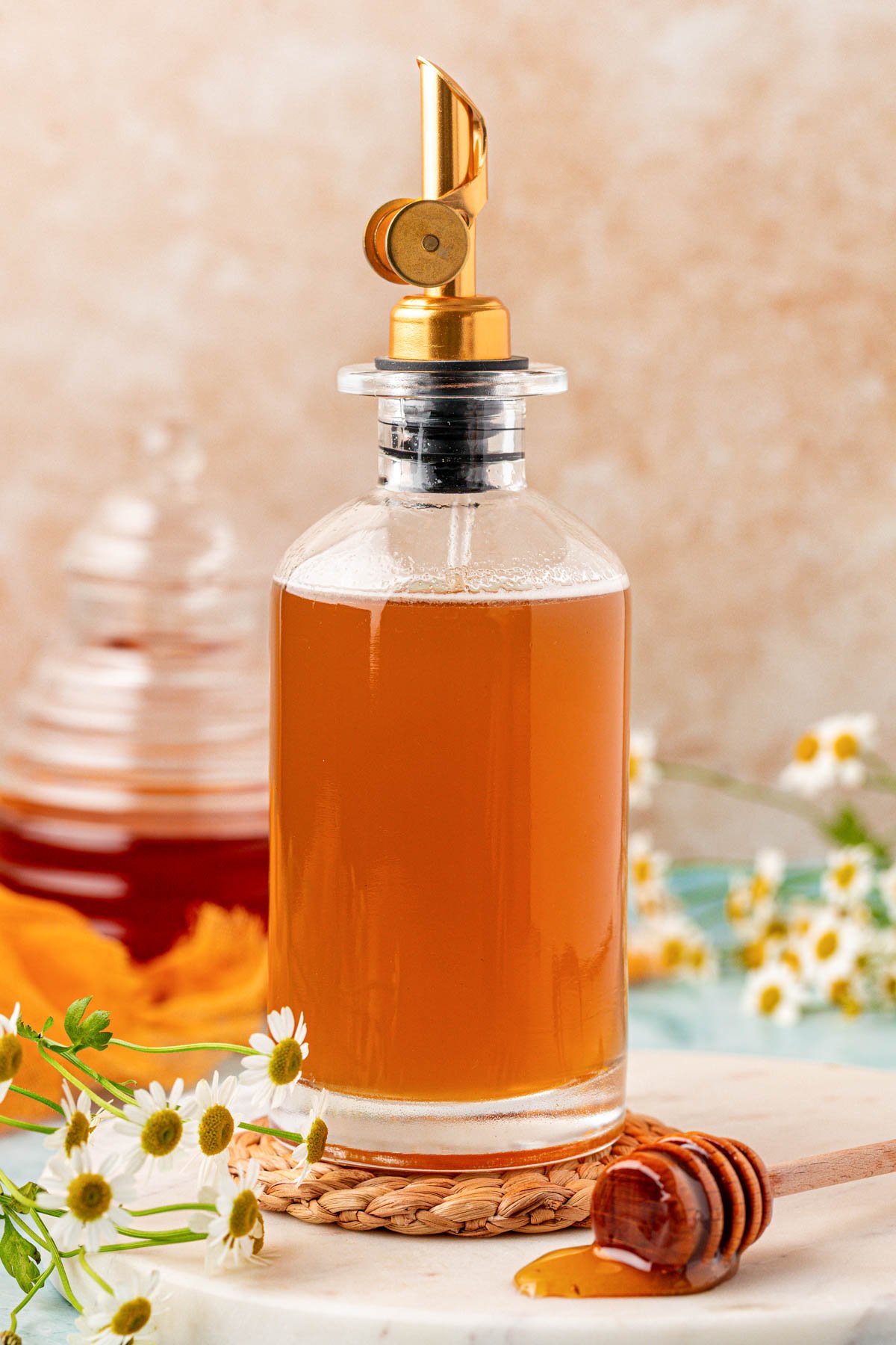 A glass bottle of honey simple syrup on a rope coaster.
