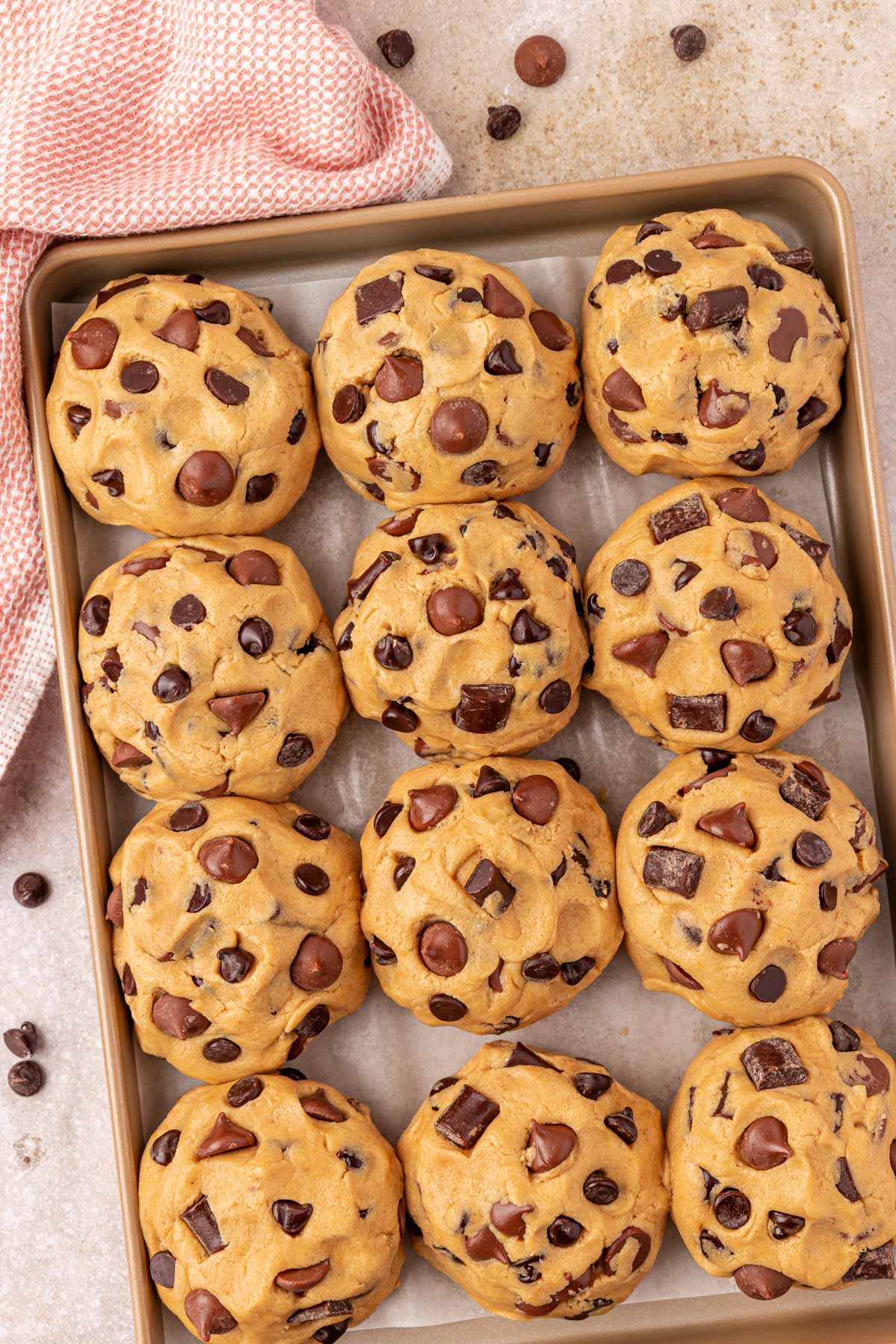 Overhead photo of balls of chocolate chunk cookie dough on a baking pan ready to chill.