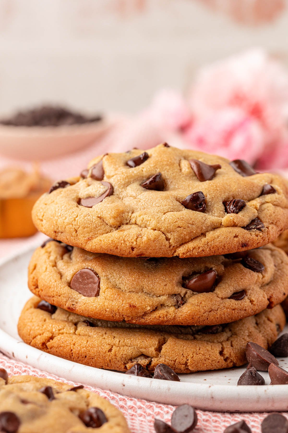 Stack of three large peanut butter chocolate chip cookies on a white plate.
