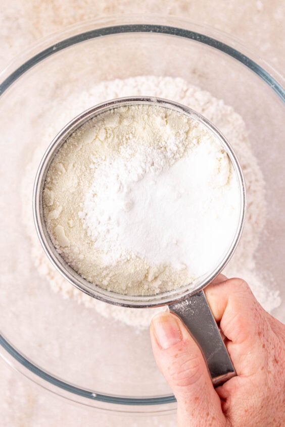 A woman's hand using a sifter for baking.