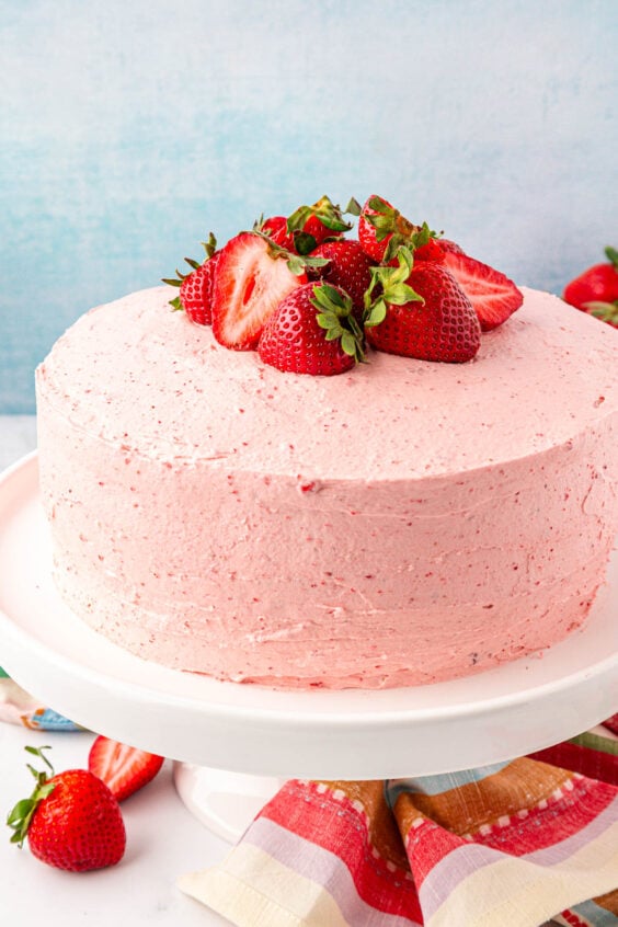 Strawberry cake on a white cake stand.