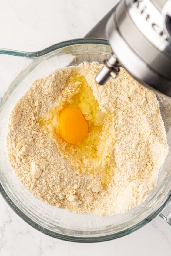 Egg being added to dry ingredients in mixing bowl for cake batter.