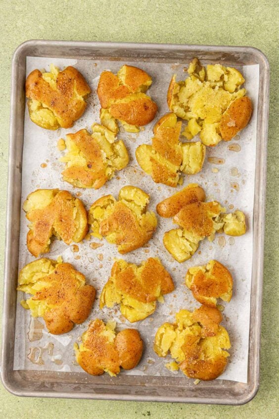 Smashed potatoes on a baking pan ready to be roasted.